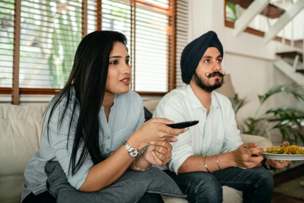 Serious ethnic couple watching movie on sofa